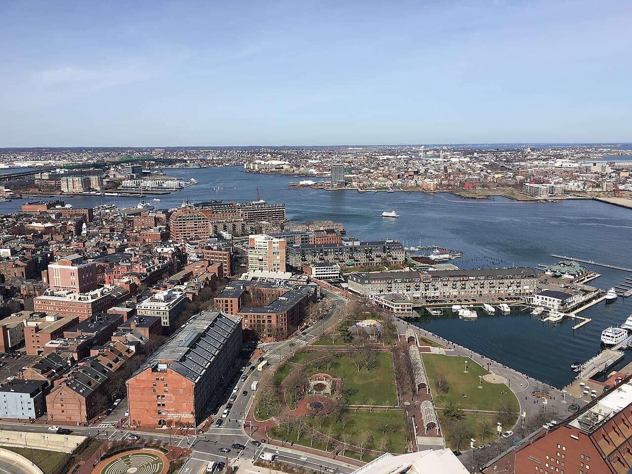 Christopher Columbus Waterfront Park and the wharves along Atlantic Avenue in Boston seen from above, with the harbor behind them