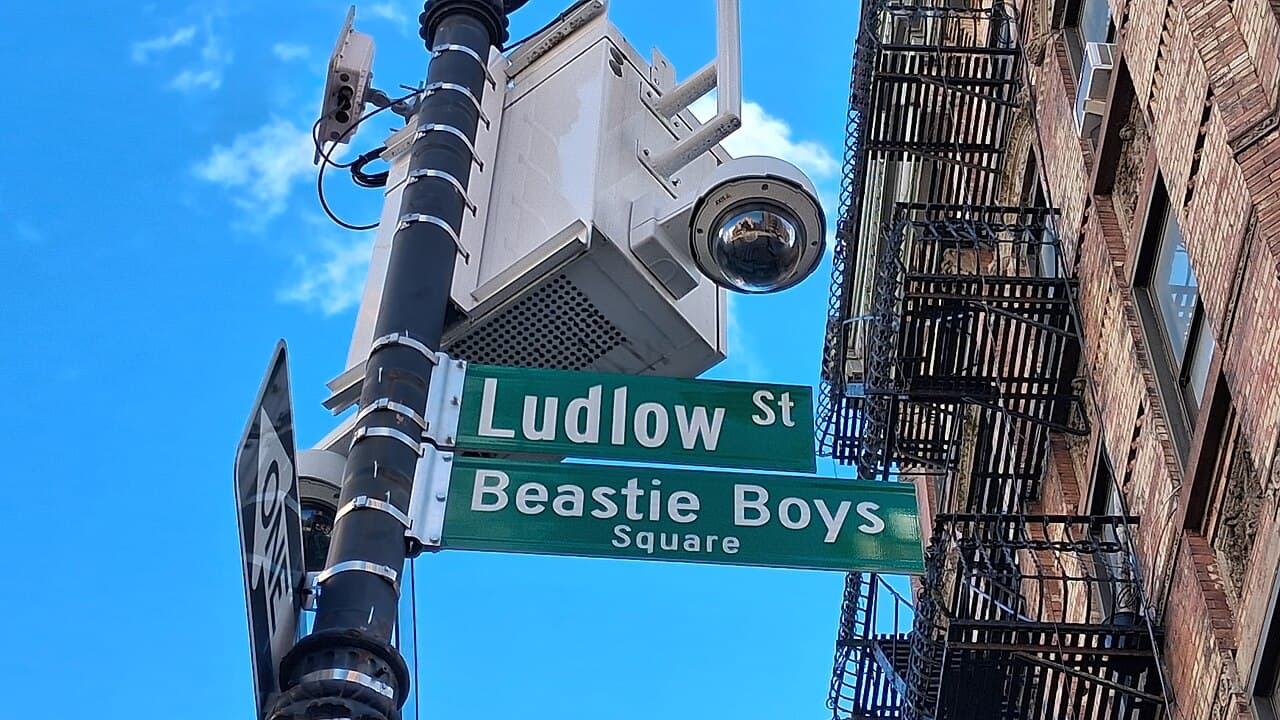 Street signs for Ludlow Street and Beastie Boys Square on the Lower East Side, with fire escapes behind them