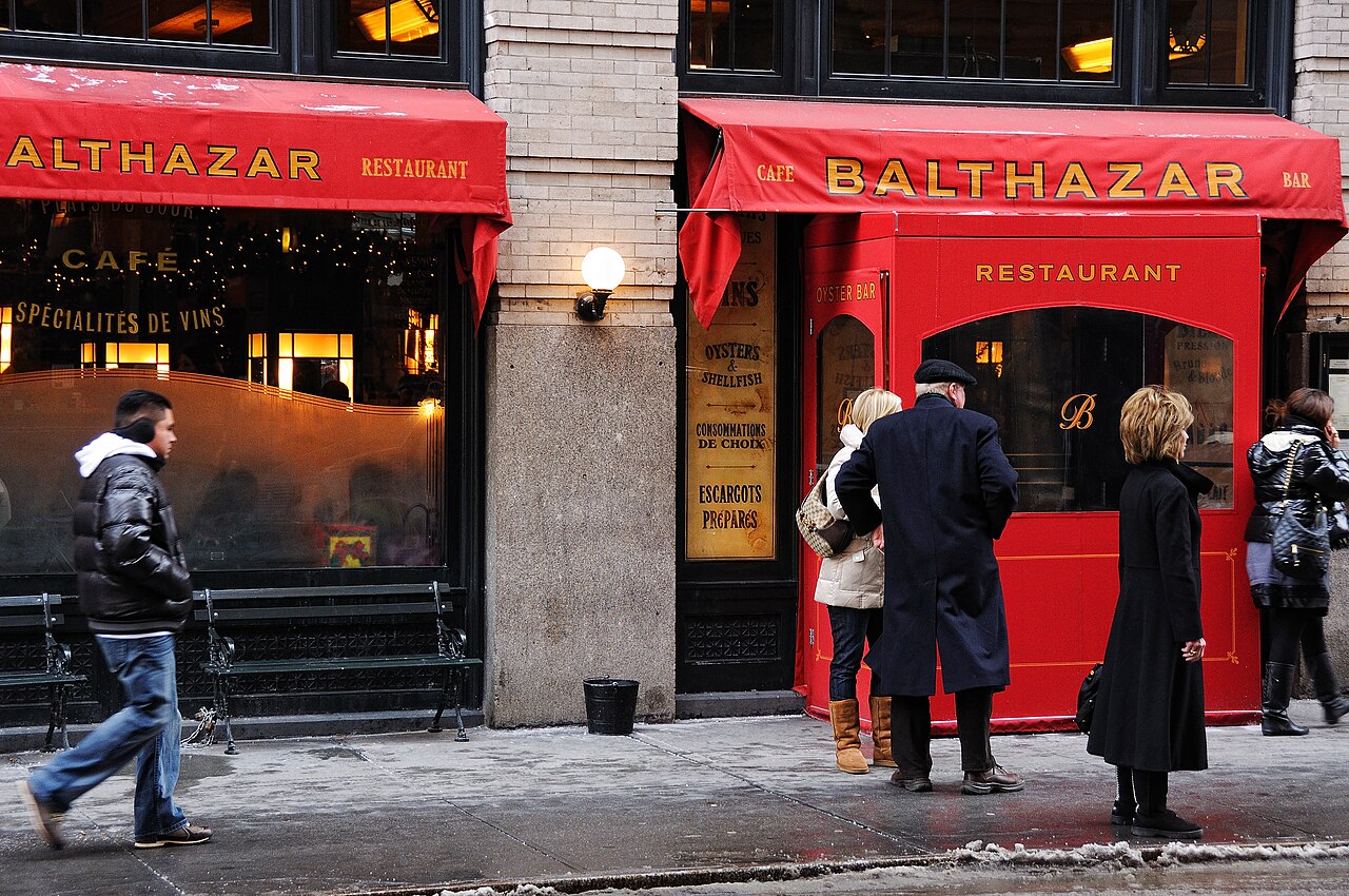 Balthazar's red awnings and red entrance on Spring Street in SoHo, with people waiting outside on a winter day