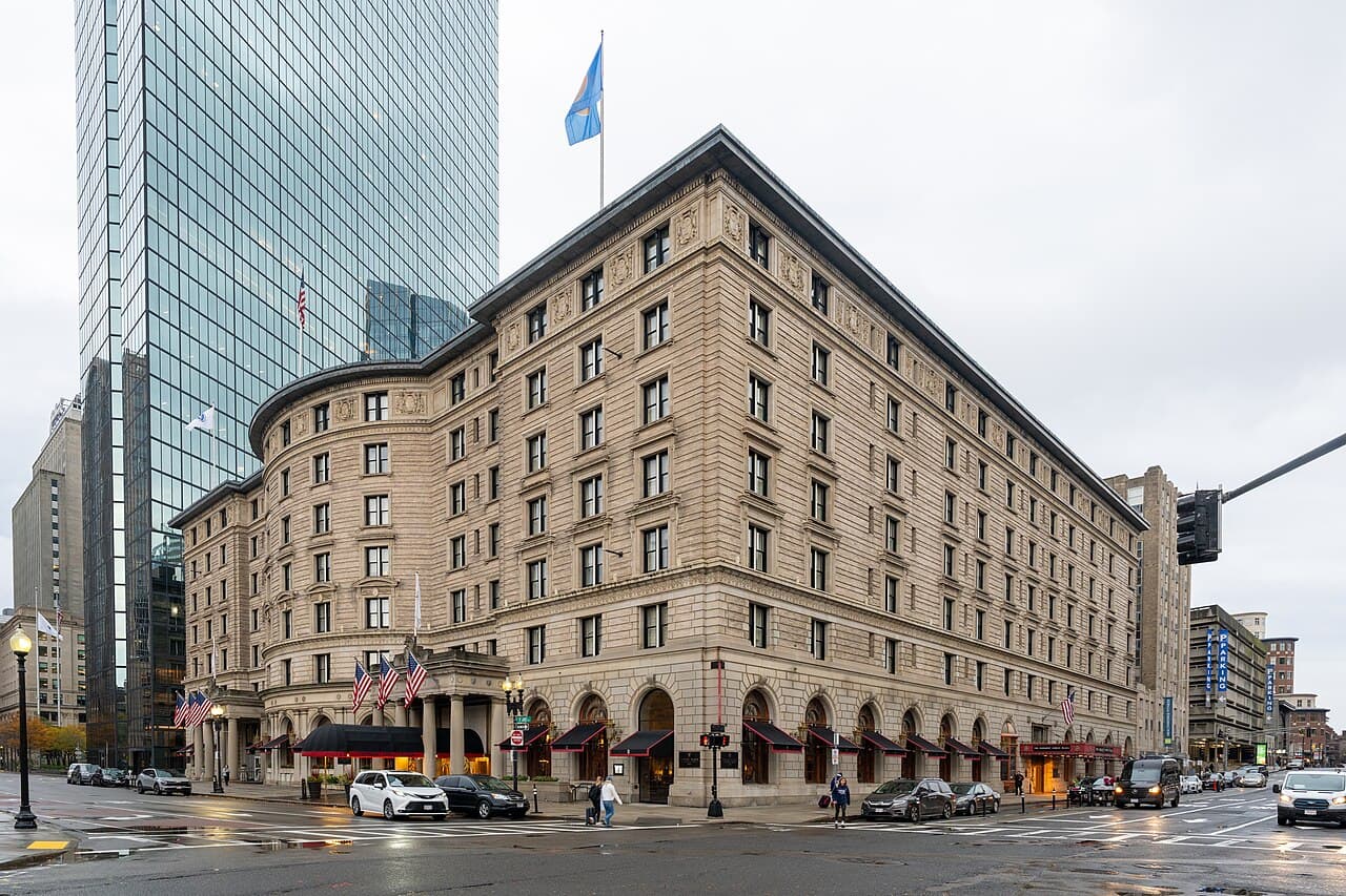 The stone front of the Copley Plaza hotel on St. James Avenue in Back Bay, with the glass Hancock tower behind it