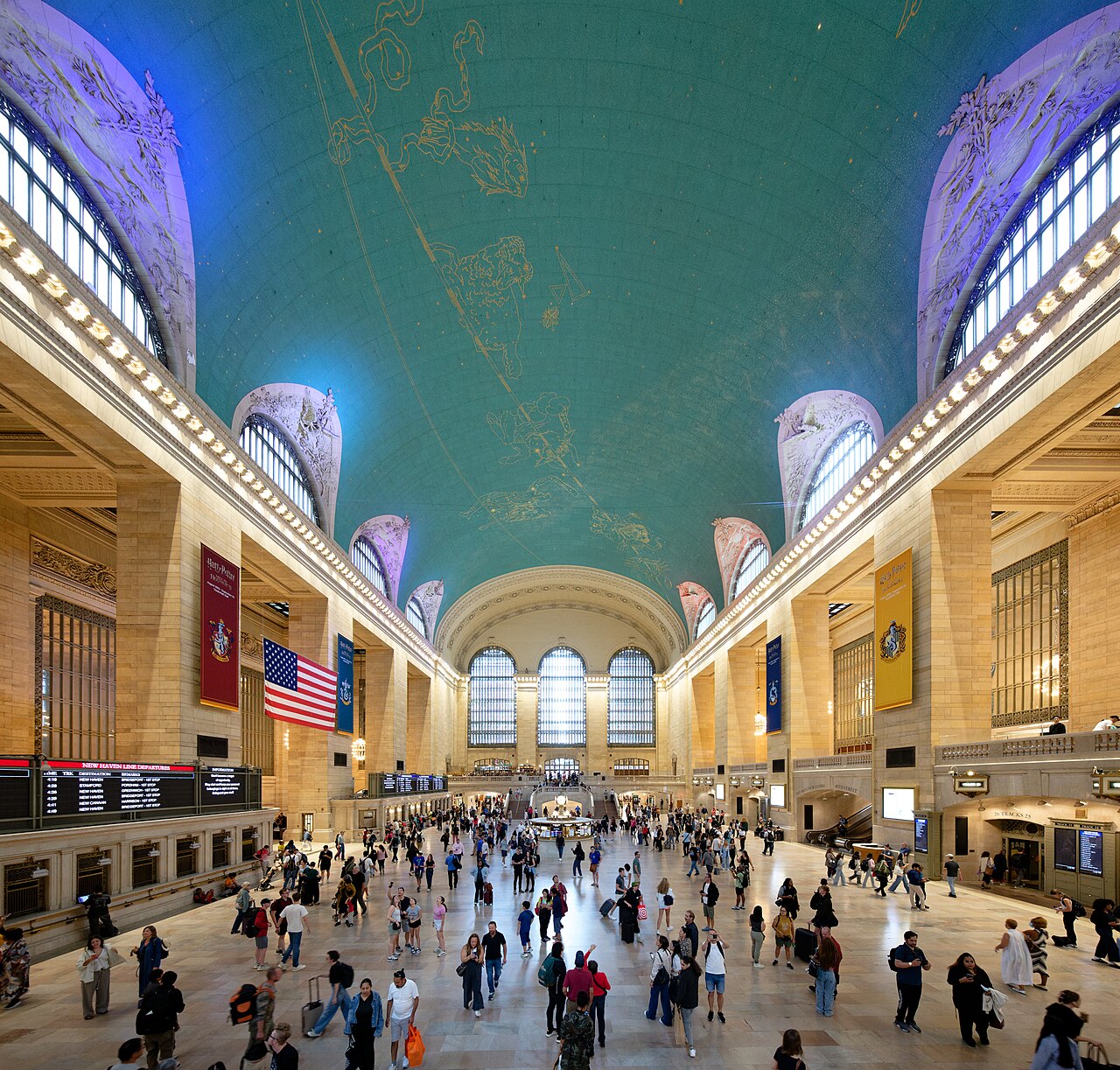 The main concourse of Grand Central Terminal under its painted ceiling, with commuters crossing the floor