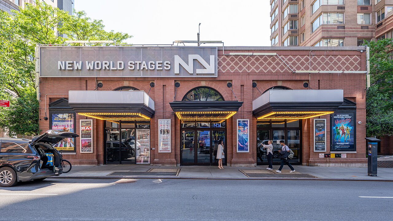 The New World Stages entrance on West 50th Street, with show posters between three lit doorways