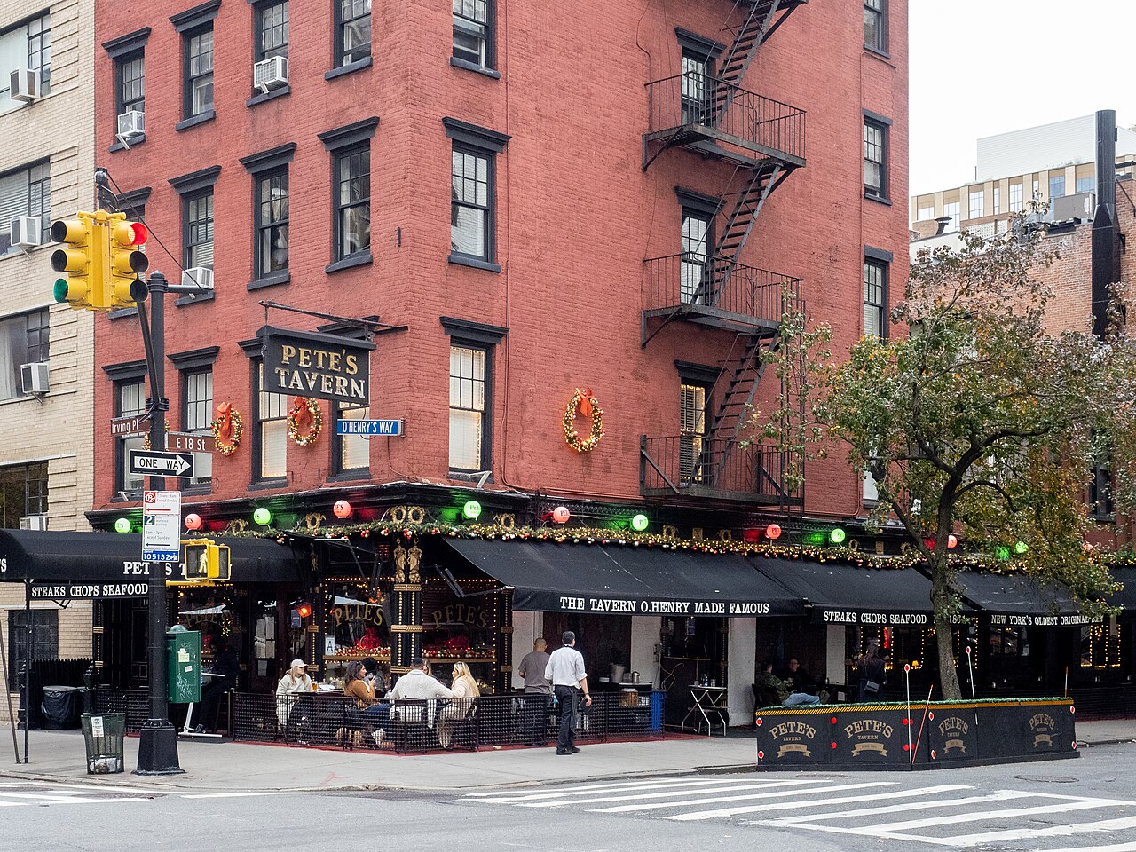 Pete's Tavern's red brick corner building on Irving Place, with people at its sidewalk tables