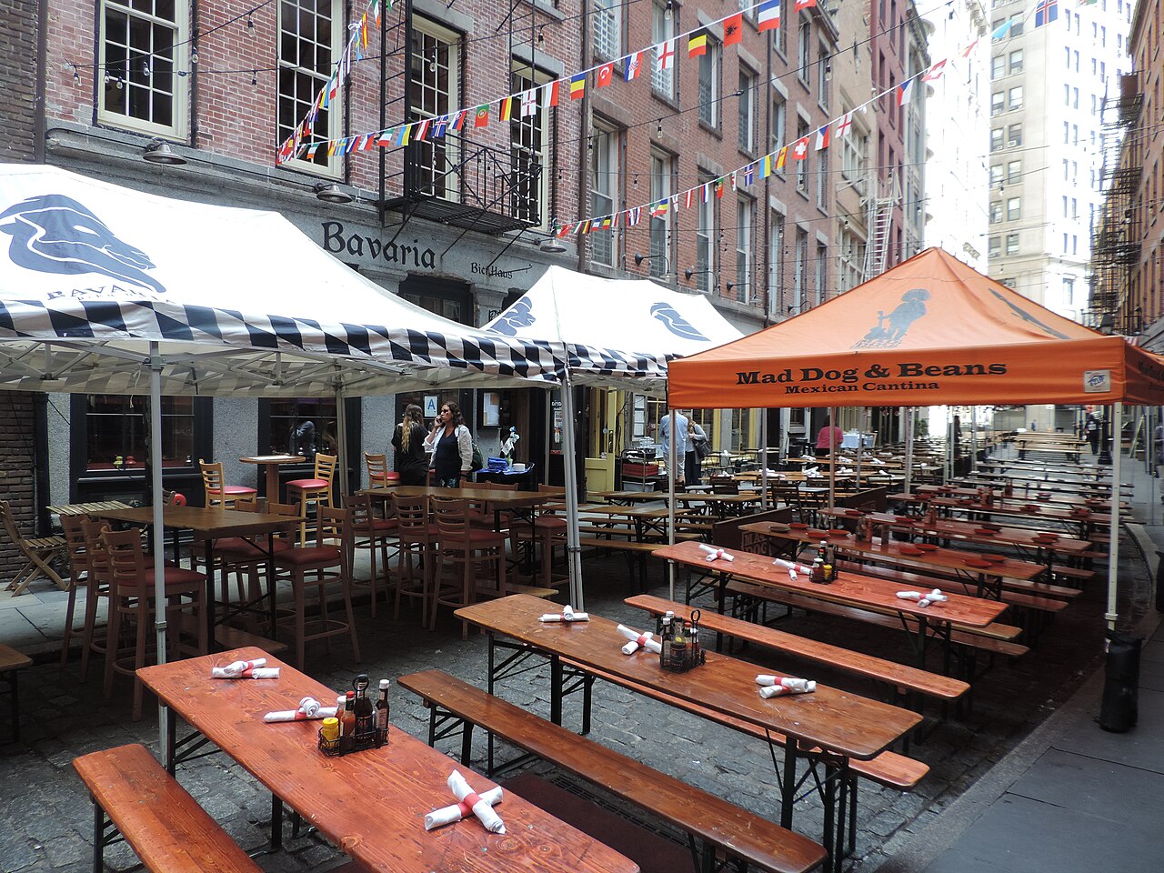 Long wooden tables and benches set out on Stone Street in the Financial District, under restaurant awnings
